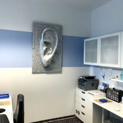Ein modernes Büro in der Reichart-Filiale Dachau mit einem großen Wandbild eines Ohrs. Professionelle Beratung und Hörgeräteanpassung in Dachau.