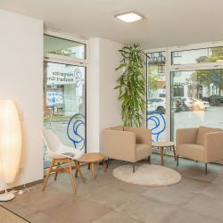 Moderner und komfortabler Wartebereich der Hörgeräte Reichart Filiale in Oberhaching, ideal für Kunden, die auf ihre Hörgeräteanpassung warten.