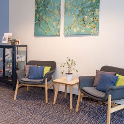 Gemütlicher Wartebereich der Reichart-Filiale in Dachau mit bequemen Sesseln und einem Couchtisch. Ihr Experte für Hörgeräte in Dachau.