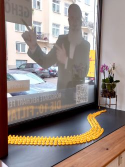 Schaufenster der Hörgeräte Reichart Filiale in Schwabing-West – kombiniert kreative Dekoration und Werbung für Hörakustik-Dienstleistungen.