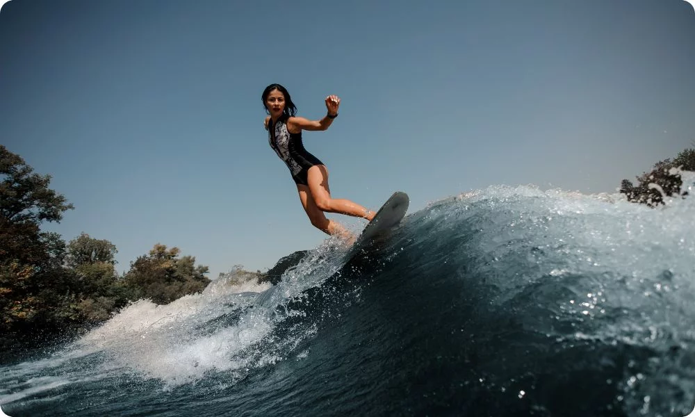Gehörschutz für Surfen und Wassersport / Frau mit Surfbrett im Meer